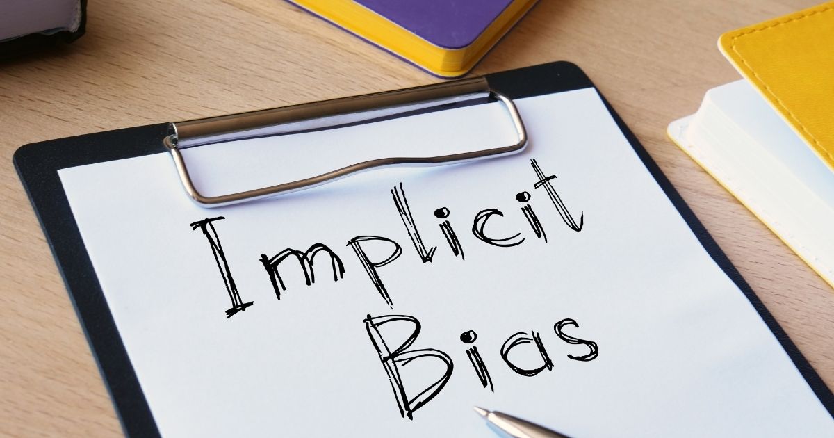 "Implicit Bias", written on a piece of paper attached to a black clipboard.