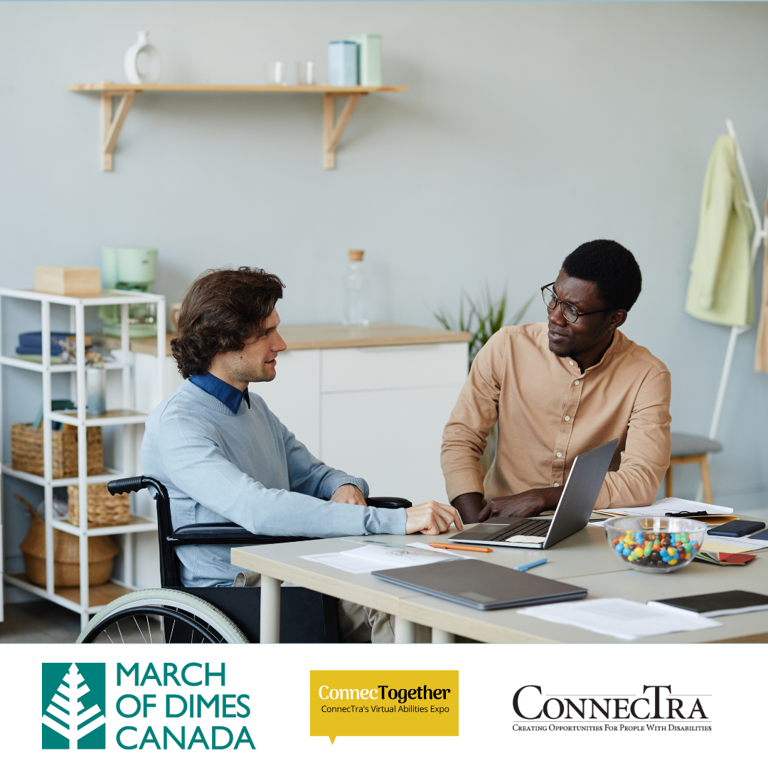 Two people sit at a desk, facing each other in conversation.